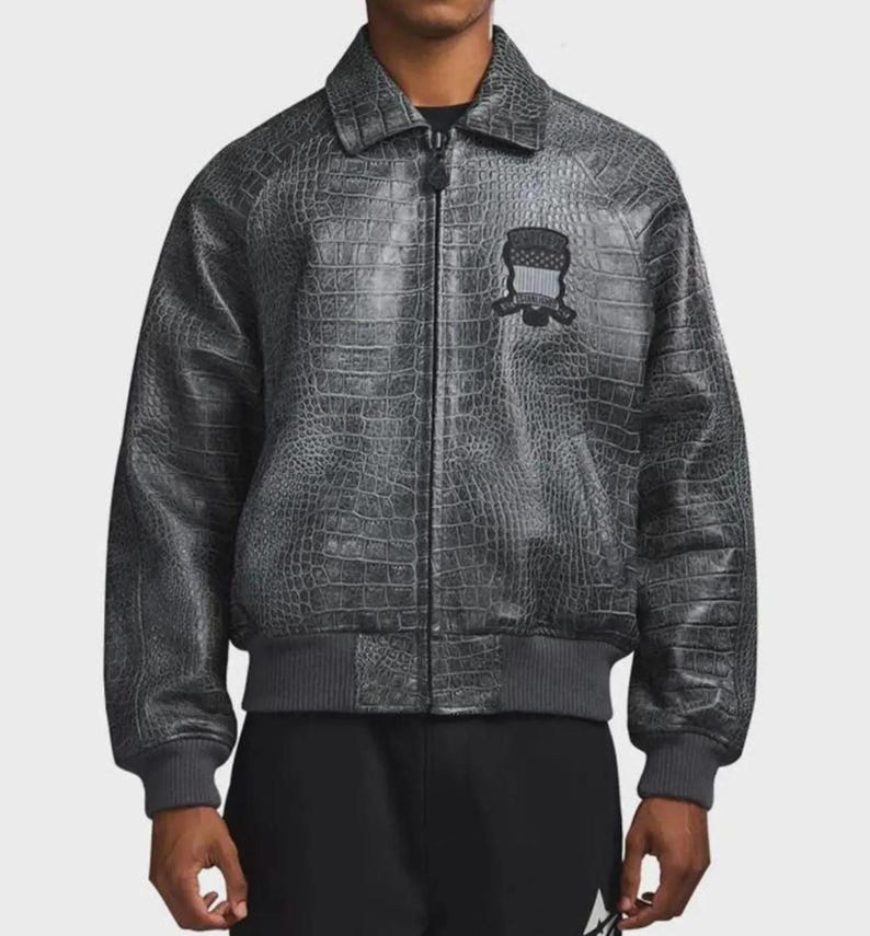 May include: A charcoal gray zip-up jacket featuring a textured crocodile skin pattern throughout. The garment includes a classic collar, ribbed cuffs and hem, and a black embroidered patch on the left chest with the text Supreme New York.