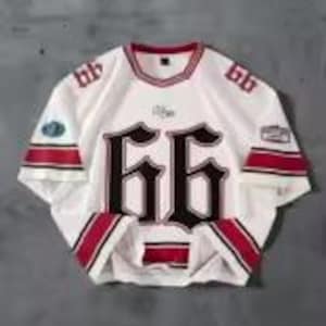 May include: White hockey jersey with red and black accents. The number "66" is prominently displayed on the front and sleeves in a gothic font. The jersey has a round neckline and a patch on the left sleeve.