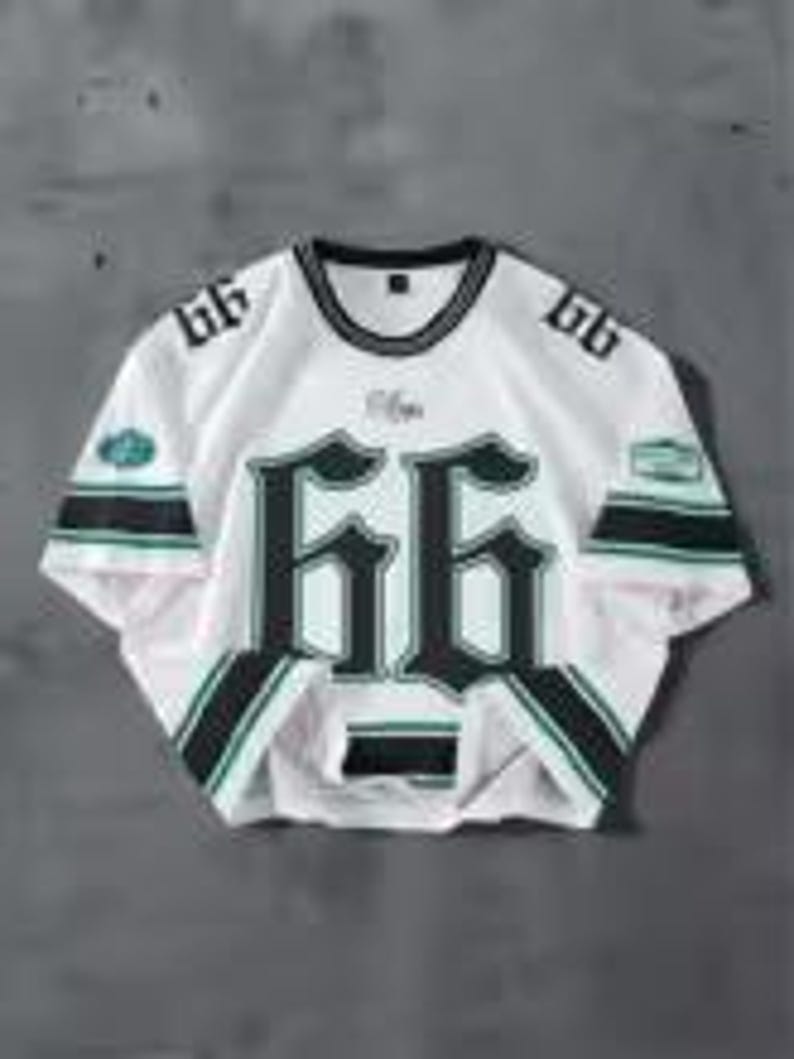 May include: White mesh jersey with the number "66" in a bold, dark green font across the front. The jersey has black and green stripes on the sleeves and a black collar. The number "66" is also on the shoulders.