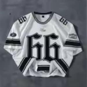 May include: White short-sleeve jersey with black accents and the number "66" prominently displayed on the front. The jersey features black stripes on the sleeves and collar, with additional text and logos. The jersey is laid flat on a gray surface.