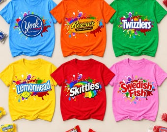 May include: Six short-sleeve t-shirts in blue, orange, green, yellow, red, and pink, each featuring a colorful paint splatter design and a candy brand logo: York, Reese's, Twizzlers, Lemonhead, Skittles, and Swedish Fish, with matching candy.
