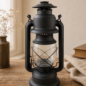 May include: A matte black metal hurricane lantern featuring a clear glass globe protected by a wire cage. The base of the lantern is embossed with the text E.T. WRIGHT CO. It has a top handle and a chimney vent, standing on a circular base.