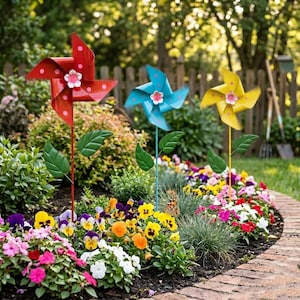 May include: Three colorful pinwheel garden decorations in red, blue, and yellow, each with a flower center and green leaves. They are set in a vibrant flower bed with a brick border, creating a cheerful outdoor scene.