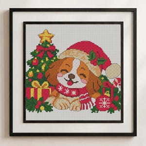 May include: A framed cross-stitch pattern featuring a brown and white puppy wearing a red Santa hat and a red and white scarf. The puppy is surrounded by a decorated Christmas tree, wrapped gifts, holly leaves, and a red ornament with a snowflake.