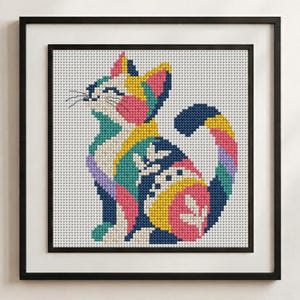 May include: A framed cross-stitch embroidery featuring a stylized cat composed of geometric color blocks in shades of navy blue, bright pink, yellow, teal, and lavender against a white grid background, enclosed in a simple black frame.