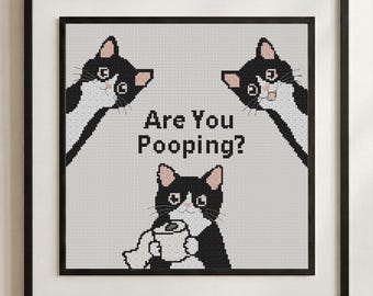 May include: A framed cross-stitch pattern featuring three black and white tuxedo cats on a light gray background. Two cats peek from the top corners, while one sits at the bottom holding a roll of toilet paper. The text reads, Are You Pooping?