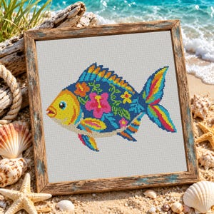 Pode incluir: Uma moldura de madeira quadrada contendo um bordado em ponto cruz de um peixe. O peixe apresenta uma cabe&ccedil;a amarela, um corpo azul-escuro com flores de hibisco cor-de-rosa e laranja, e uma cauda multicolorida com riscas amarelas, azuis e vermelhas.