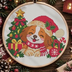 May include: A cross-stitch embroidery in a round wooden hoop featuring a brown and white puppy wearing a red Santa hat and a red scarf. The puppy is surrounded by a decorated Christmas tree, wrapped gifts, holly leaves, and a red ornament.