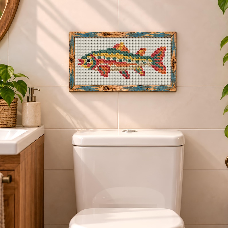 May include: A rectangular cross-stitch artwork featuring a multi-colored fish with yellow, red, and teal patterns on a white grid fabric. The piece is enclosed in a weathered, distressed wooden frame with blue and brown textured detailing.