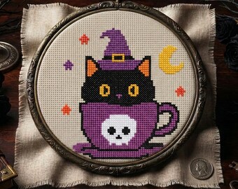 May include: A cross-stitch embroidery in a round, ornate bronze-colored frame. The design features a black cat wearing a purple witch hat, sitting inside a purple teacup decorated with a white skull. Small orange and purple stars and a yellow crescent moon surround the cat.