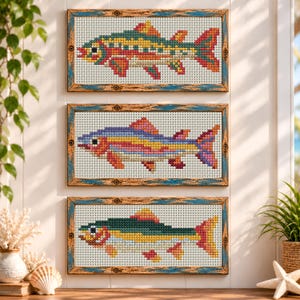 May include: Three rectangular cross-stitch art pieces featuring fish designs, each framed in distressed wood with blue accents. The top fish is green, yellow, and red; the middle is purple, yellow, and pink; the bottom is green and yellow.