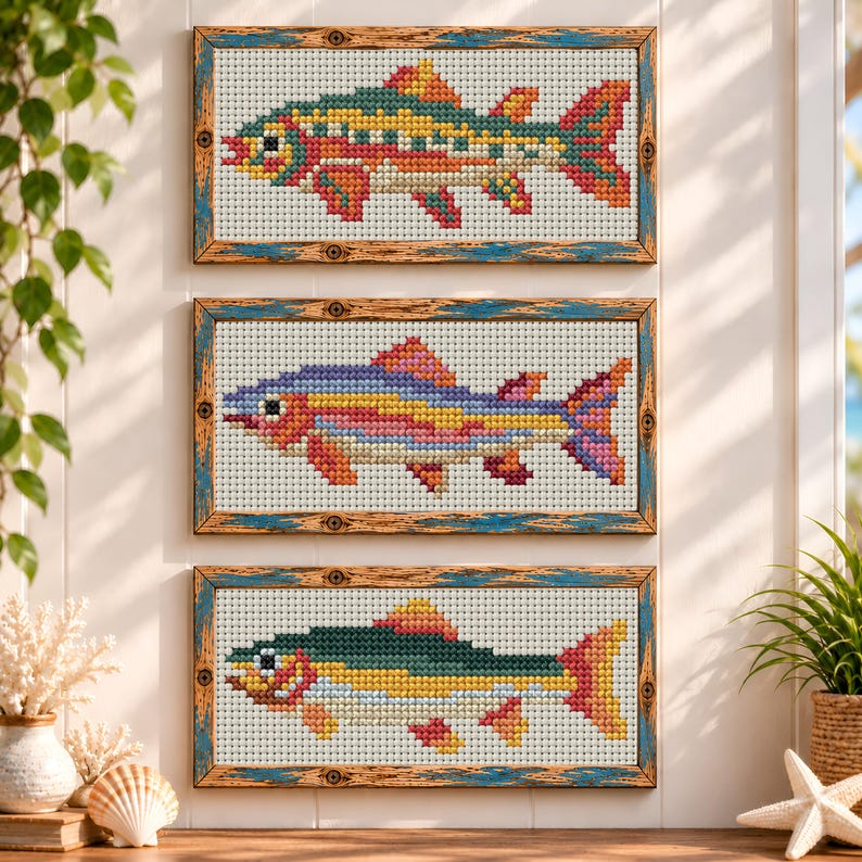May include: Three rectangular cross-stitch art pieces featuring fish designs, each framed in distressed wood with blue accents. The top fish is green, yellow, and red; the middle is purple, yellow, and pink; the bottom is green and yellow.