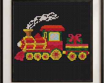 May include: A framed cross-stitch pattern on a black background featuring a red, yellow, and green steam locomotive pulling a carriage with a green gift box topped with a red bow. White stitches represent smoke rising from the train's chimney.