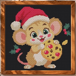 Op de afbeelding: Een ingelijst kruissteekpatroon met een lichtbruine muis die een rood-witte kerstmuts draagt. De muis heeft grote oren, groene ogen en roze wangen en houdt een geel koekje met rode en bruine vlekken vast. Groene hulstblaadjes met rode bessen zijn aan de zijkanten geplaatst tegen een donkergrijze achtergrond.