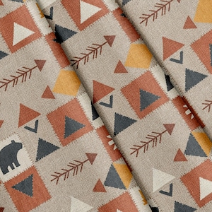 Op de afbeelding: Een beige stof met een herhalend patroon van donkergrijze berensilhouetten, oranje en donkergrijze driehoeken, gele vierkanten en donkergrijze pijlen. Het ontwerp is gerangschikt in een raster met stikselachtige randen rond de vormen.