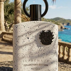 Puede incluir: Un frasco de perfume rectangular blanco con motas negras, tapa y asa negras. La botella tiene la inscripci&oacute;n "SUPREMACY COLLECTOR'S EDITION AFNAN". Un emblema negro est&aacute; en la parte delantera.