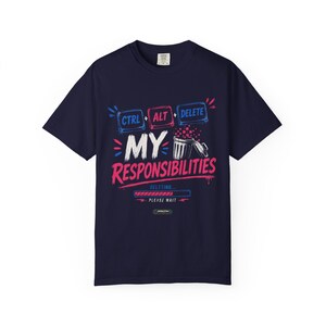 May include: A navy blue short-sleeve t-shirt featuring a graphic print with the text CTRL + ALT + DELETE MY RESPONSIBILITIES. The design includes a trash can icon, a loading bar labeled DELETING, and the text PLEASE WAIT in white, red, and blue.
