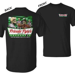 Pode incluir: Uma t-shirt preta com um gr&aacute;fico nas costas e um log&oacute;tipo mais pequeno na frente. O gr&aacute;fico das costas mostra esqueletos numa sala com luz verde e o texto Private Pyle's JELLY DOUGHNUTS THEY'RE PAYING FOR IT, YOU EAT IT. Log&oacute;tipo na frente.