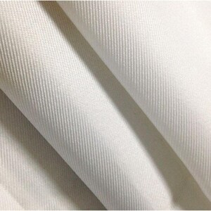 Pode incluir: Um tecido branco s&oacute;lido com um padr&atilde;o de trama diagonal distinto. O material est&aacute; dobrado, criando drapeados suaves e fluidos e sombras que destacam a textura e a cor branca limpa e consistente da superf&iacute;cie do material t&ecirc;xtil.