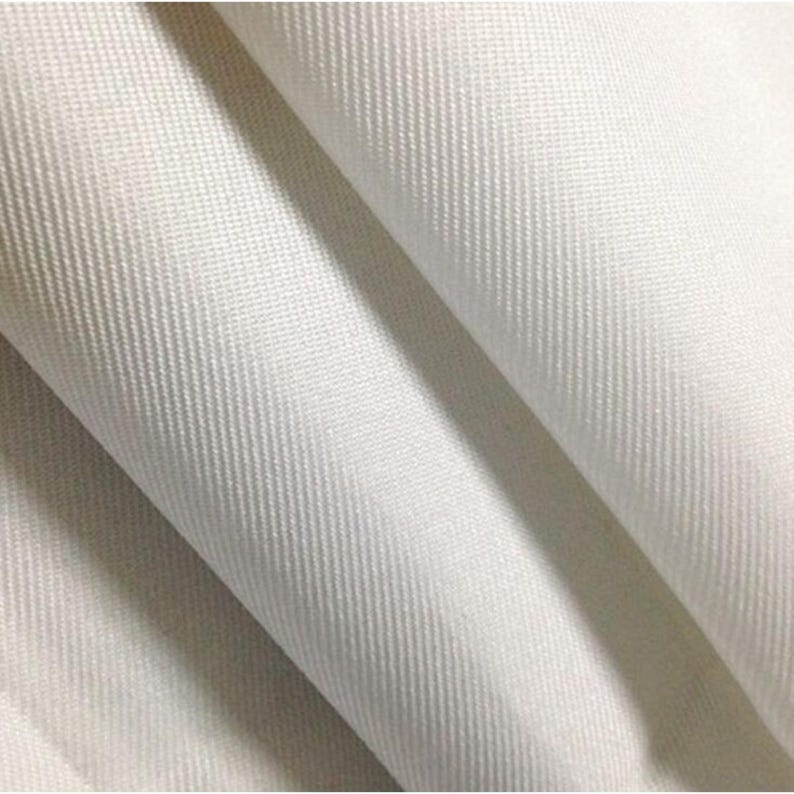 Pode incluir: Um tecido branco s&oacute;lido com um padr&atilde;o de trama diagonal distinto. O material est&aacute; dobrado, criando drapeados suaves e fluidos e sombras que destacam a textura e a cor branca limpa e consistente da superf&iacute;cie do material t&ecirc;xtil.