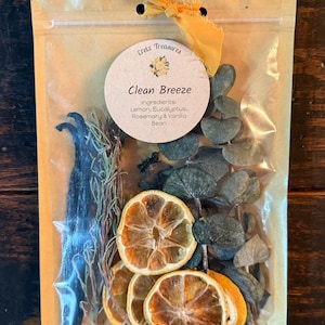 May include: A clear pouch containing dried lemon slices, eucalyptus leaves, rosemary sprigs, and vanilla beans. A round label reads Eretz Treasures, Clean Breeze, Ingredients: Lemon, Eucalyptus, Rosemary & Vanilla Bean. A yellow ribbon is tied at the top.