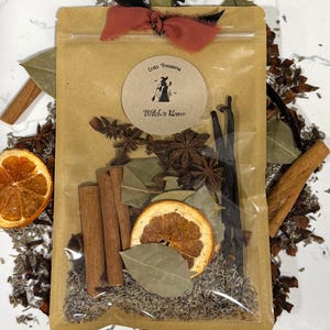 Puede incluir: Una bolsa de papel marrón con ventana transparente que contiene rodajas de naranja seca, ramas de canela, anís estrellado, vainas de vainilla y lavanda. Una etiqueta circular dice Eretz Treasures Witch's Brew. Un lazo color óxido.