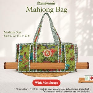 May include: A green fabric bag with a floral and bird pattern, featuring a central letter A monogram, striped handles, and integrated straps holding a rolled bamboo mat. The bag measures 22 inches long, 11 inches high, and 6 inches wide.
