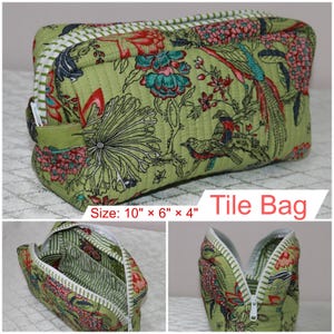 May include: A quilted fabric bag with a green base featuring a floral and bird print in red, blue, and black. It has a white zipper closure and measures 10 inches by 6 inches by 4 inches. The text Tile Bag is printed on the image.
