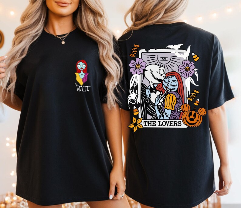 May include: A black t-shirt featuring a small graphic of Sally on the front left chest with the text "Mrs. Watt". The back displays a large tarot card illustration of Jack and Sally titled "THE LOVERS" with bats, flowers, and pumpkins.