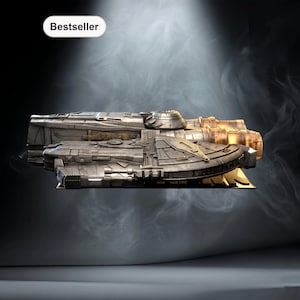 Op de afbeelding: Een gedetailleerd model van een ruimteschip, voornamelijk zilver met gouden accenten, wordt getoond tegen een rokerige, donkere achtergrond. Het model heeft ingewikkelde panelen en motordetails. Het woord "Bestseller" staat in een witte ovaal linksboven.