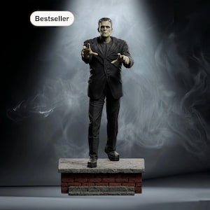 Op de afbeelding: Een beeldje van Frankenstein, gekleed in een zwart pak, staat op een bakstenen en stenen platform. De figuur heeft een groene huid en reikt naar voren. Het woord "Bestseller" staat in een witte ovaal linksboven.