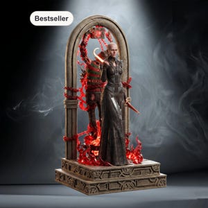 Op de afbeelding: Gedetailleerd beeld van een vrouw in een lange zwarte jurk die een mes vasthoudt, staand voor een figuur in een gestreepte trui. De scène wordt omlijst door een boog met rode, vurige accenten en een basis met gebeeldhouwde details. Het woord "Bestseller" staat linksboven.