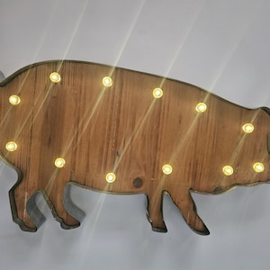 Puede incluir: Decoración de pared con forma de cerdo de madera con luces LED blancas cálidas. El cerdo tiene un acabado rústico de vetas de madera y un contorno de metal. Una pieza de acento encantadora e iluminada para el hogar o negocio.