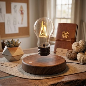 May include: A levitating light bulb with a warm, glowing filament sits above a wooden base. A succulent in a geometric pot and a leather-bound journal are also on the table. The light bulb is a unique home decor item.
