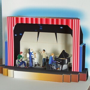 May include: A pop-up card depicting a jazz band on stage. The stage features a red curtain, a black backdrop, and a bandstand. Musicians play a guitar, saxophone, trumpet, and piano. The card is made of paper and has a three-dimensional effect.