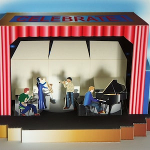 May include: A pop-up card featuring a stage with a band playing instruments. The stage has red curtains and the word "CELEBRATE!" across the top. The band includes a guitarist, a saxophonist, a trumpet player, and a pianist.