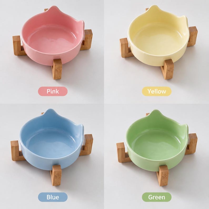 May include: Four ceramic bowls with cat-ear shaped rims, each resting on a light brown wooden stand. The bowls are available in pastel pink, yellow, light blue, and light green. Each bowl is labeled with its corresponding color name below it.