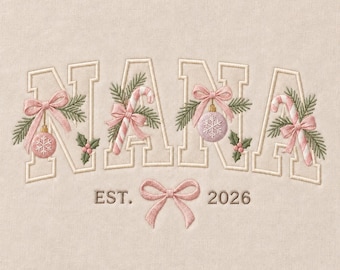 May include: An embroidered design on light beige fabric featuring the word NANA in large block letters. The letters are decorated with pink bows, candy canes, pine needles, holly berries, and snowflake ornaments. Below, the text EST. 2026 is centered with a pink bow.