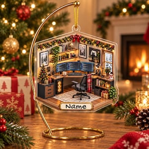May include: A hexagonal hanging ornament featuring a miniature home office scene with three computer monitors, a desk chair, shelves, and a small Christmas tree. The ornament is suspended from a gold metal stand and includes a label with the text Name.