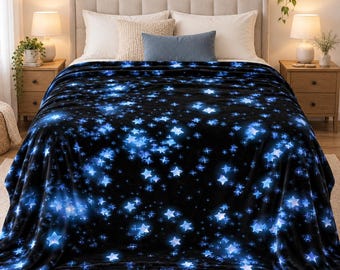 May include: A plush fleece blanket featuring a dark black background with a vibrant pattern of glowing blue stars and celestial sparkles scattered across the fabric, creating a deep space effect that covers the entire surface of the bedding.