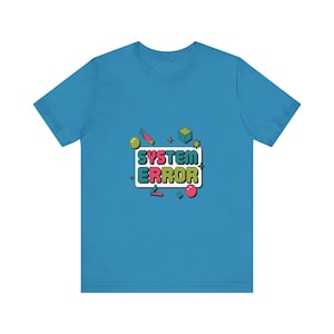 May include: A bright blue short-sleeve t-shirt featuring a central graphic with the text "SYSTEM ERROR" in colorful block letters. The design includes various small geometric shapes like cubes, spheres, and stars in shades of green, pink, and blue.