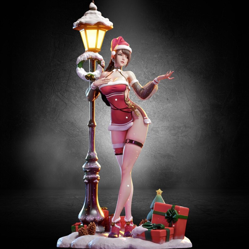 以下が含まれることがあります： サンタ風の衣装を着た女性のクリスマスをテーマにしたフィギュア。雪に覆われた街灯に寄りかかっている。サンタ帽、白いトリムの赤いドレス、ハイヒールを着用。プレゼントとクリスマスツリーがベースにあります。