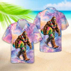May include: A short-sleeve button-down shirt featuring a graphic of a brown Bigfoot wearing sunglasses and a floral lei, carrying a surfboard, and wearing floral swim trunks. The shirt has a swirling purple, pink, and orange tie-dye background.