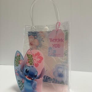 May include: Clear plastic gift bag with a handle, featuring a cartoon character and two surfboards. The bag has a pink tag that says "THANK YOU". The background has a floral design.