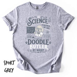 Könnte beinhalten: Ein sportgraues T-Shirt mit einer Grafik eines Hundes mit Brille und Laborkittel vor einer Tafel, versehen mit dem Text "SCIENCE TEACHER BY DAY DOODLE BUTLER BY NIGHT" und wissenschaftlichen Symbolen wie Reagenzgläsern und Büchern.