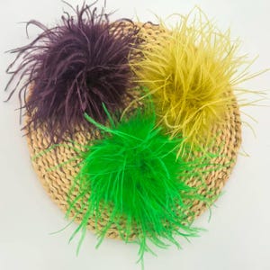 May include: Three fluffy feather clusters in deep purple, bright yellow, and vibrant green. Each cluster is composed of numerous thin, wispy plumes radiating outwards from a central point, creating a soft, voluminous, and textured appearance.
