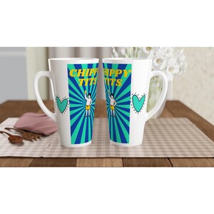 May include: Two white ceramic latte mugs featuring a central graphic with blue and teal sunburst rays. The text CHIPPY TITS appears in yellow above a cartoon figure wearing yellow shorts and holding a drink. A teal heart is printed on the side.
