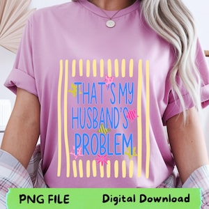 Peut inclure: T-shirt lilas avec l'inscription bleue "THAT'S MY HUSBAND'S PROBLEM", encadrée de lignes verticales jaunes. Le motif comprend des étoiles et des poissons colorés. Le bas du t-shirt porte les mentions "PNG FILE" et "Digital Download".