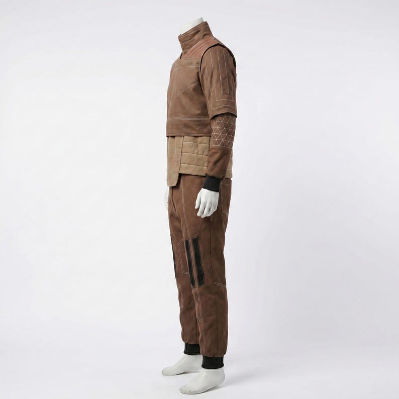 May include: A brown two-piece outfit consisting of a short-sleeved top and matching trousers. The top features a high collar, quilted paneling, and a geometric white line pattern on the sleeve. The trousers have black vertical accents on the legs.