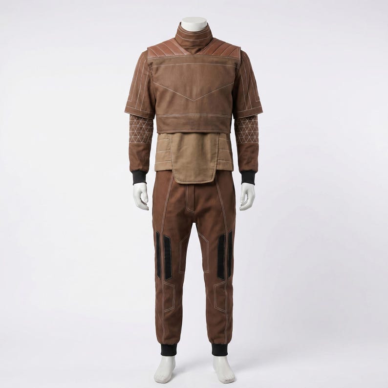 May include: A brown two-piece outfit consisting of a short-sleeved top with a high collar, quilted shoulder panels, and white stitching, paired with matching trousers featuring black vertical accents and white seam detailing on a mannequin.